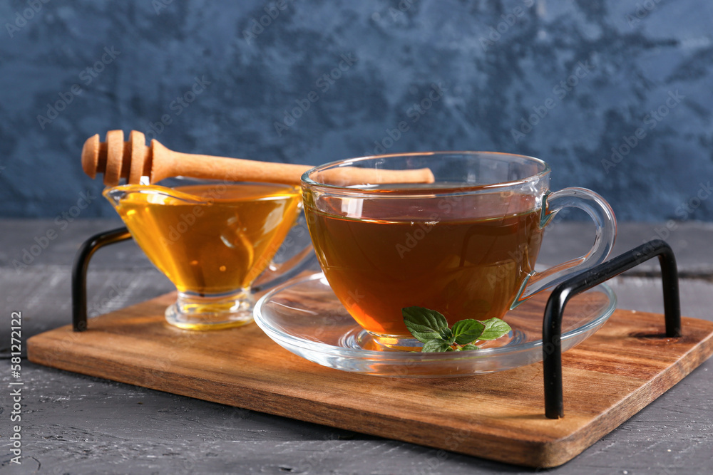 Tray with cup of green tea and honey on dark wooden table