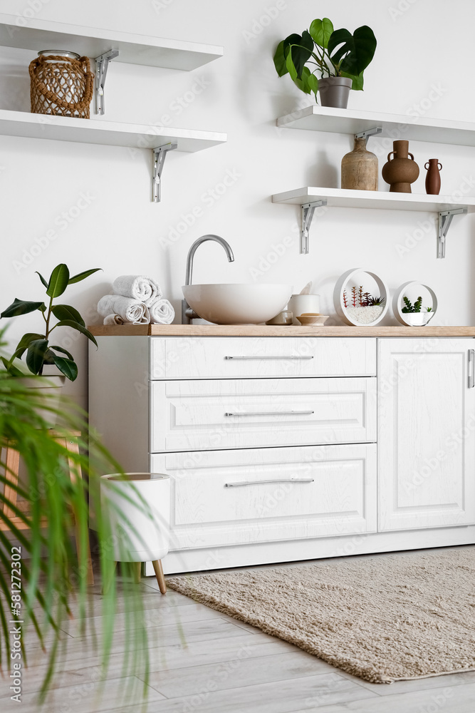 Interior of light bathroom with sink, counters and shelves