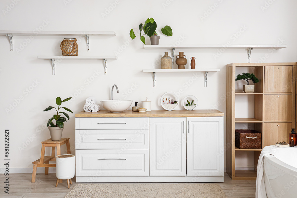 Interior of light bathroom with sink, counters and shelves