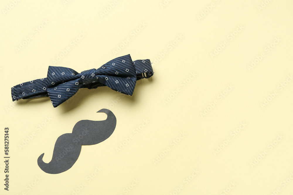 Male bow tie and paper mustache on color background