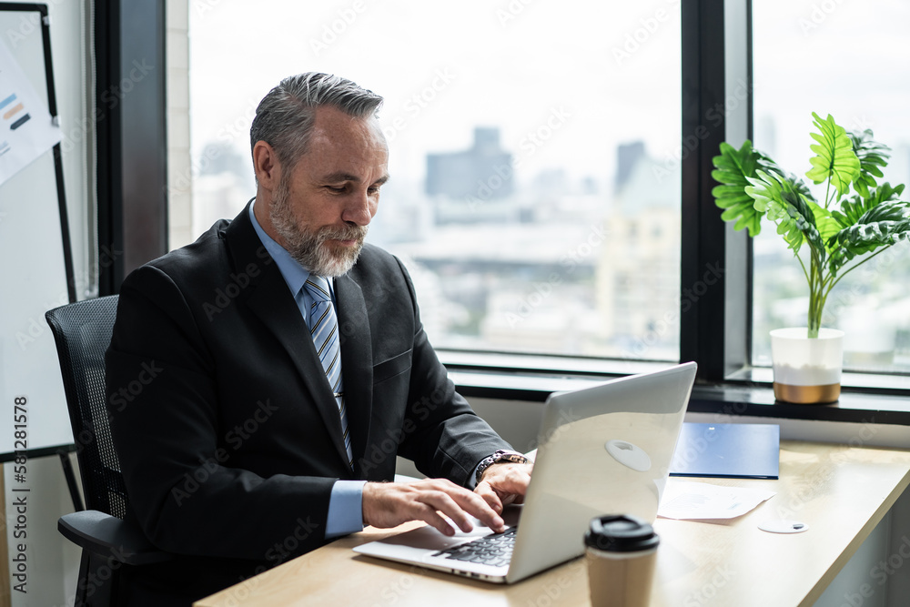 Caucasian senior businessman working on table in the office workplace. Attractive elderly mature mal