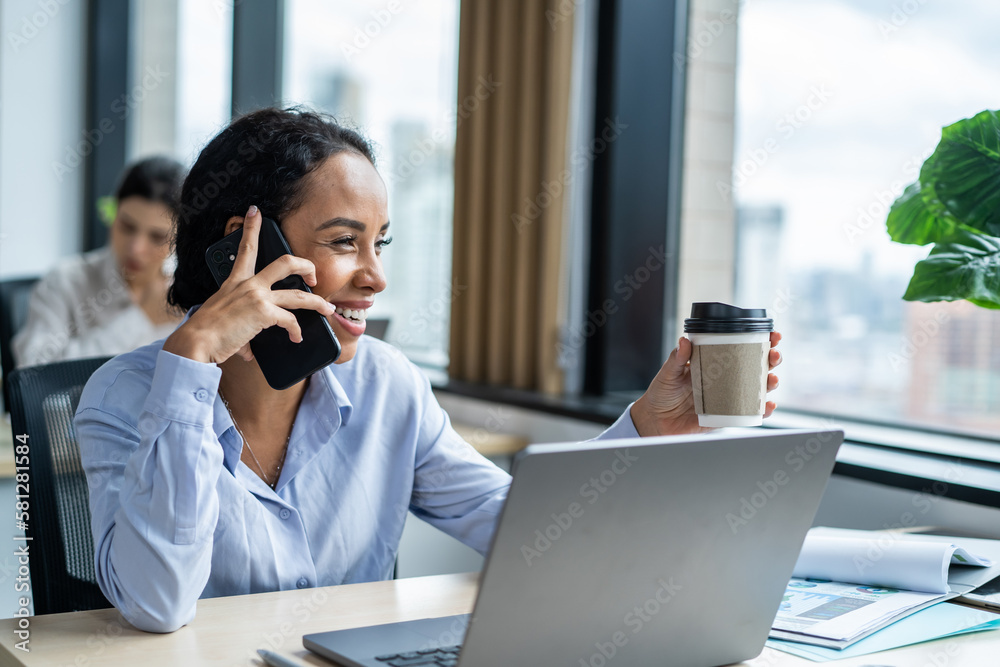 Latino happy businesswoman talking on smartphone and working in office. Attractive young girl employ