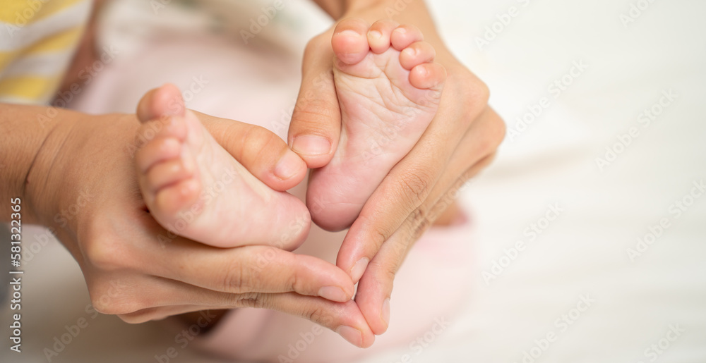 Asian Mother hands in heart shape. Baby feet in mothers hands that mean symblo of love. Mom and her