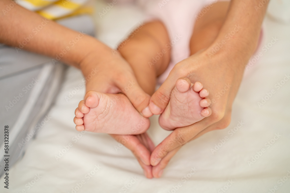 Asian Mother hands in heart shape. Baby feet in mothers hands that mean symblo of love. Mom and her