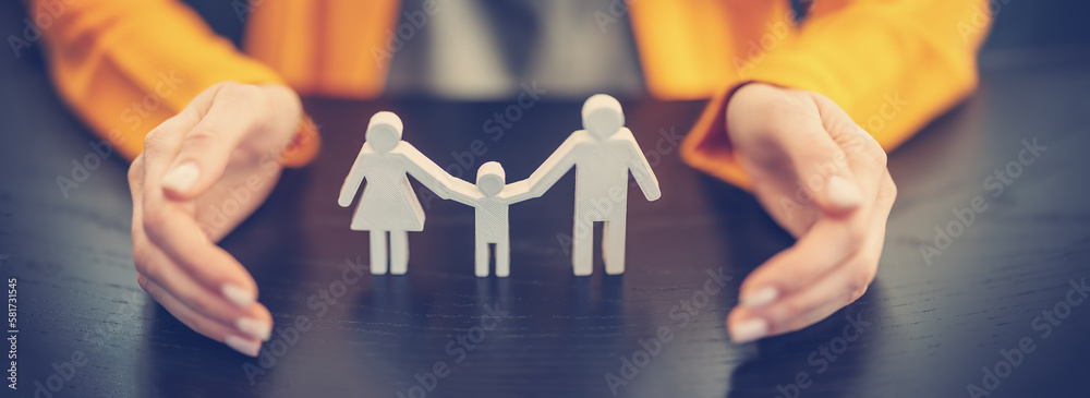 Figurine of the family surrounding by womans hands.