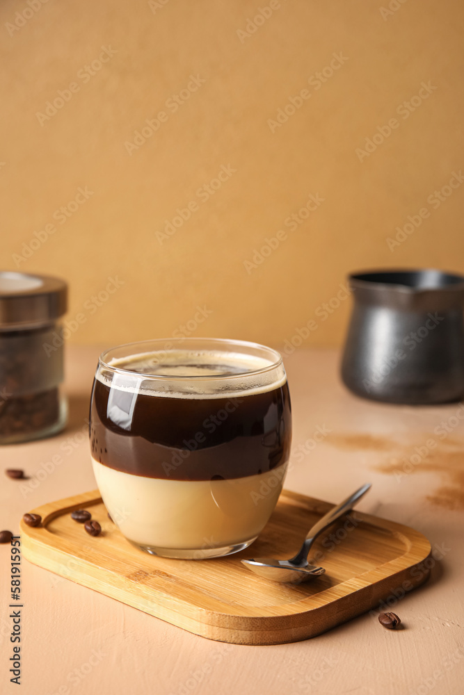 Wooden board with glass of tasty Cafe Bombon on color background