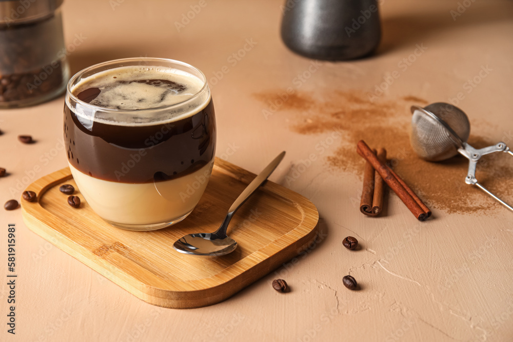 Wooden board with glass of tasty Cafe Bombon on color background