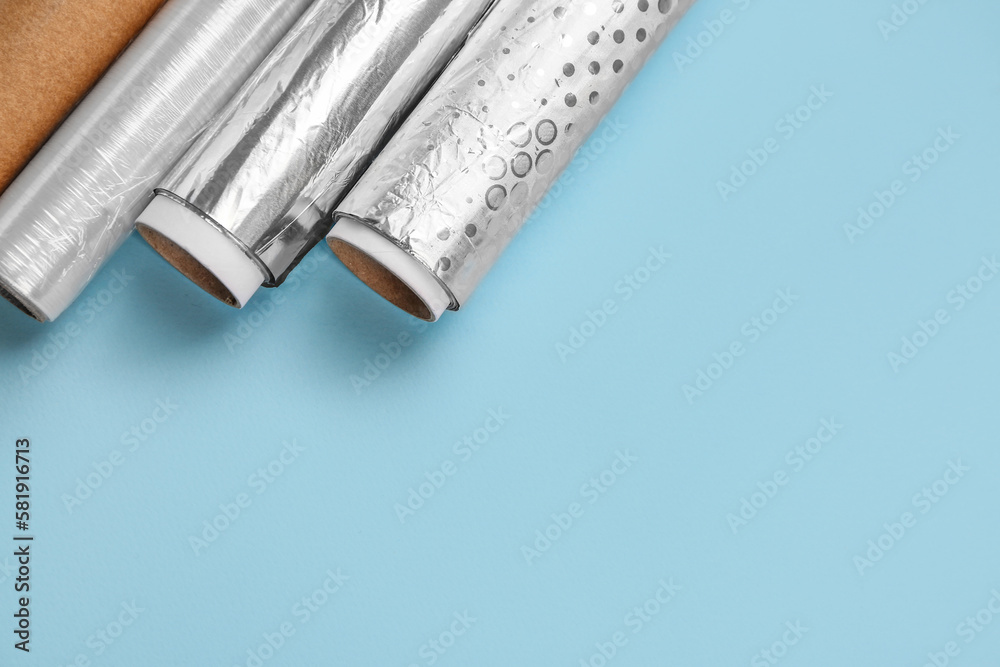 Rolls of aluminium foil and food film on color background