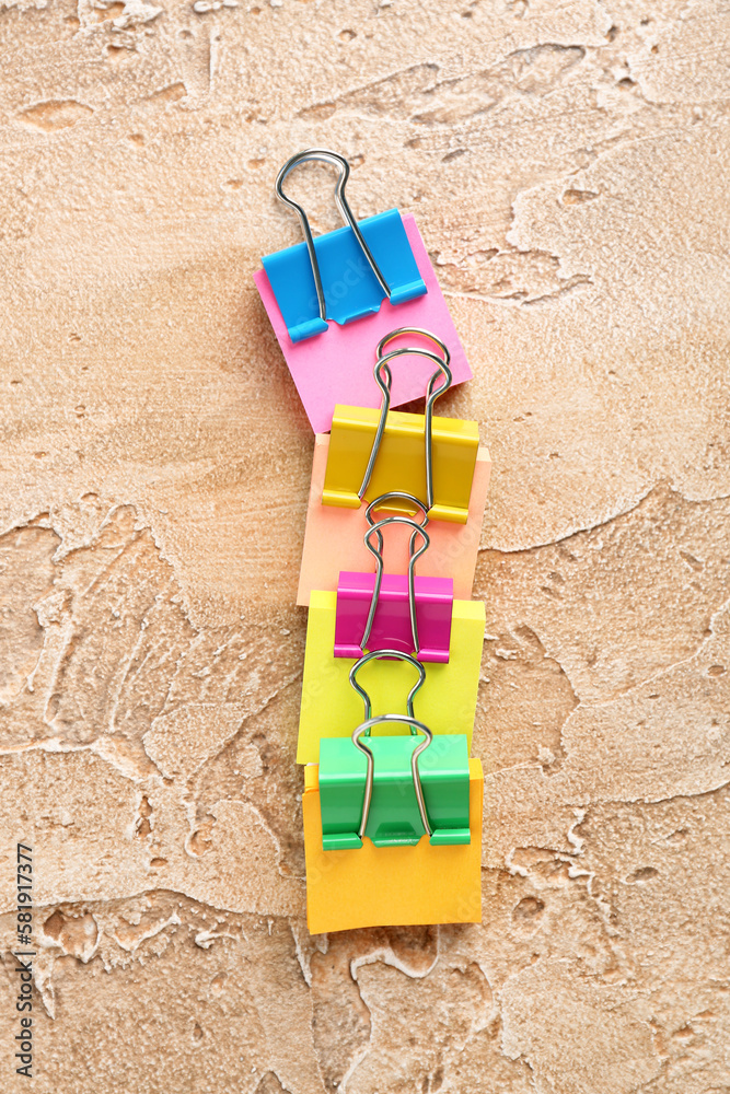 Sticky notes with colorful binder clips on color background