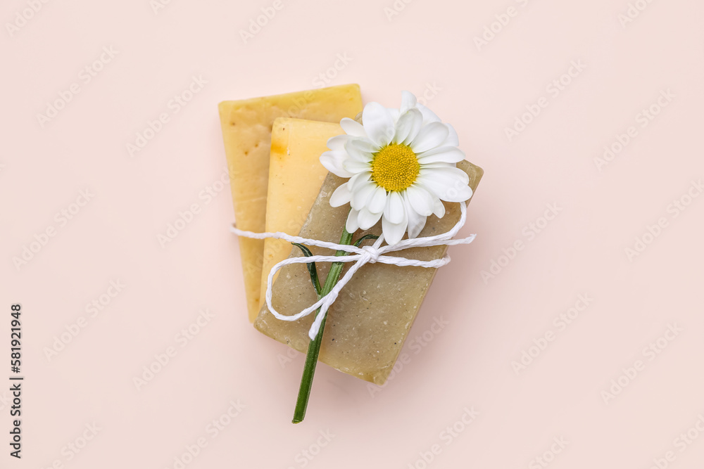 Soap bars with chamomile flower tied with rope on color background