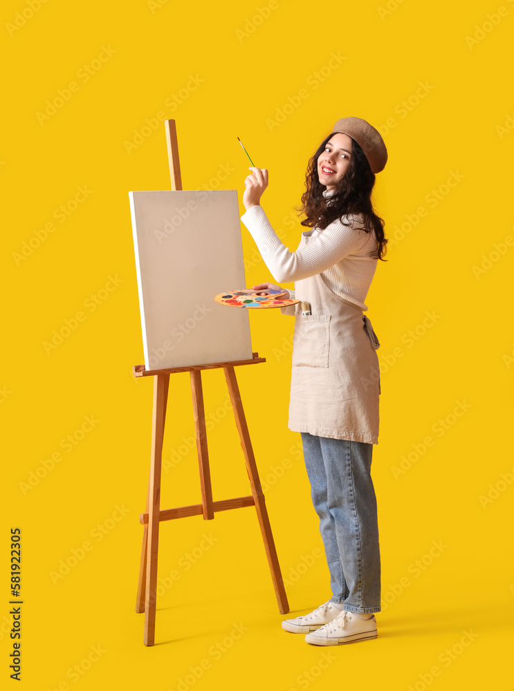 Teenage artist with brush, paint palette and easel on yellow background