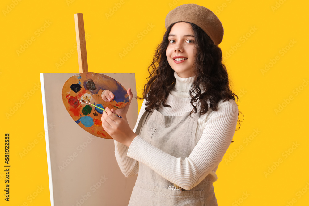 Teenage artist with brush, paint palette and easel on yellow background