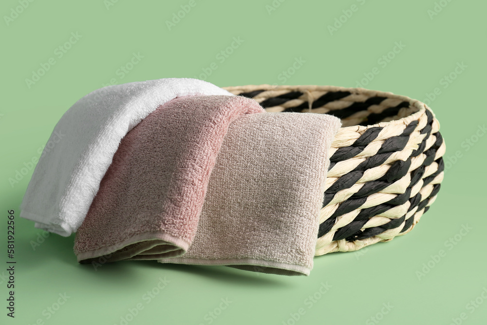 Basket with folded soft towels on green background