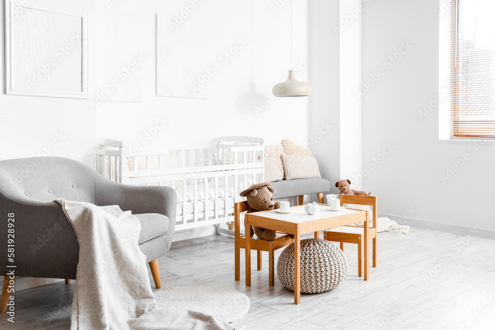 Interior of light childrens bedroom with baby crib, table and chairs