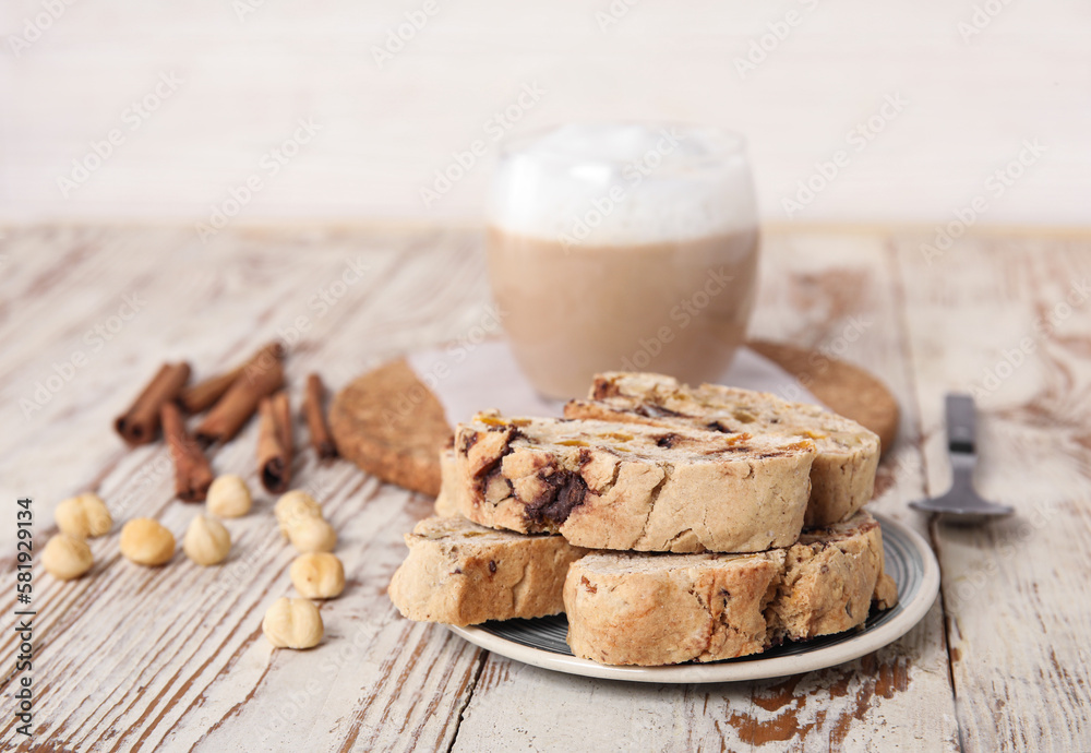 Delicious biscotti cookies, hazelnuts, cinnamon and cup of coffee on white wooden background