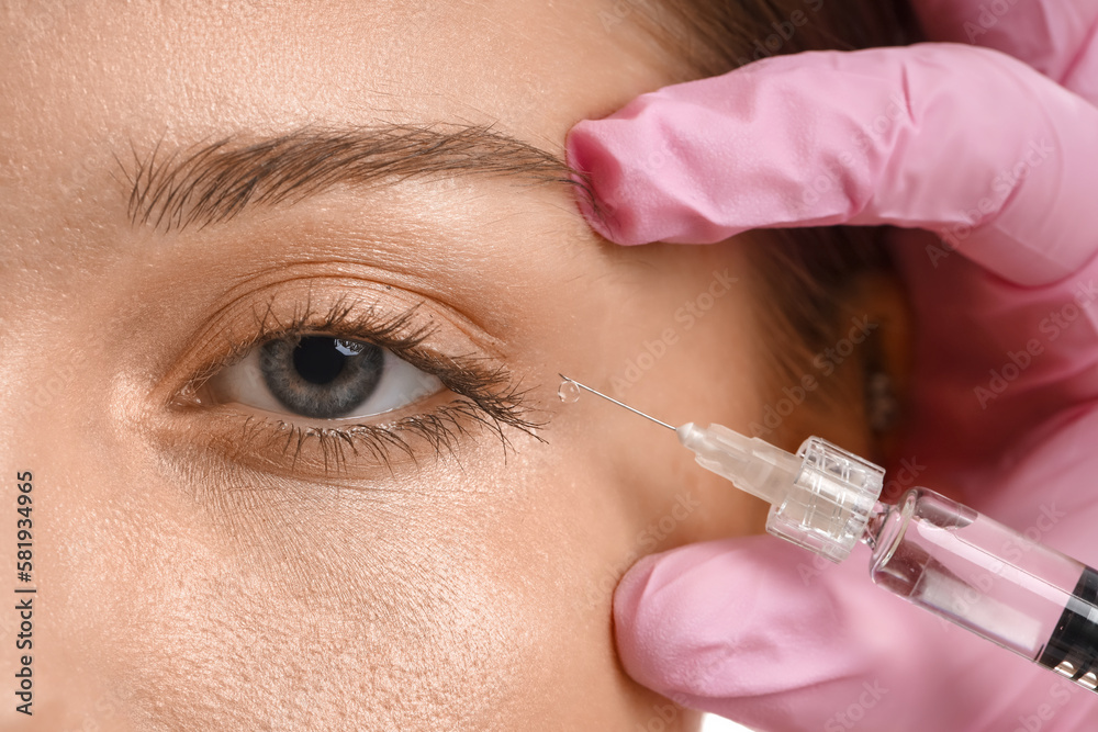 Young woman receiving filler injection in face, closeup