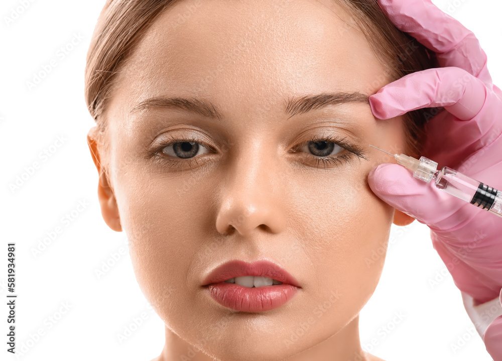 Young woman receiving filler injection in face against white background