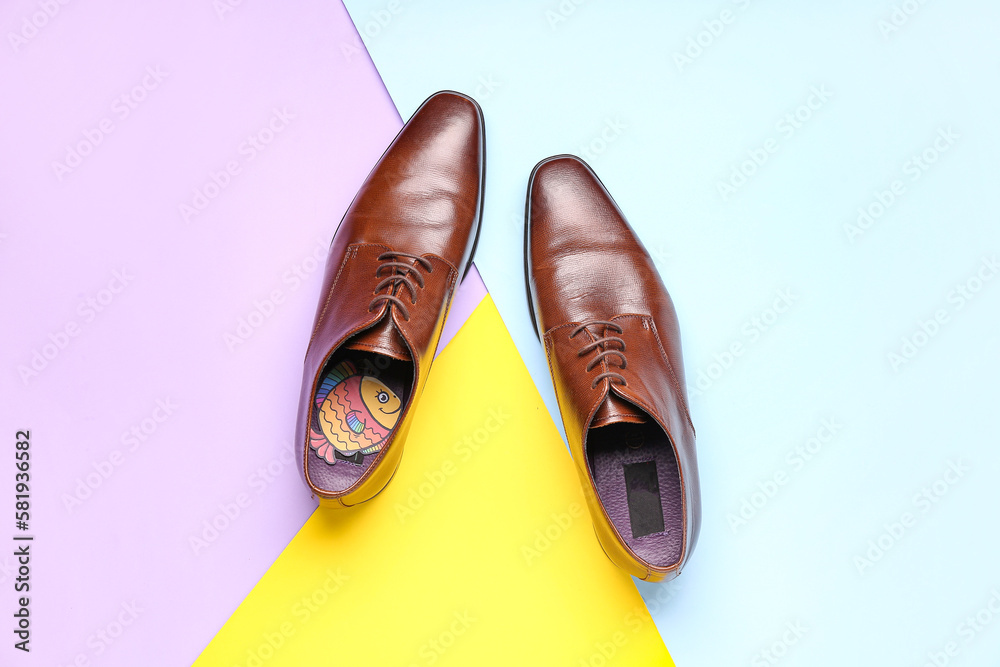 Male shoes with paper fish on color background. April Fools Day celebration