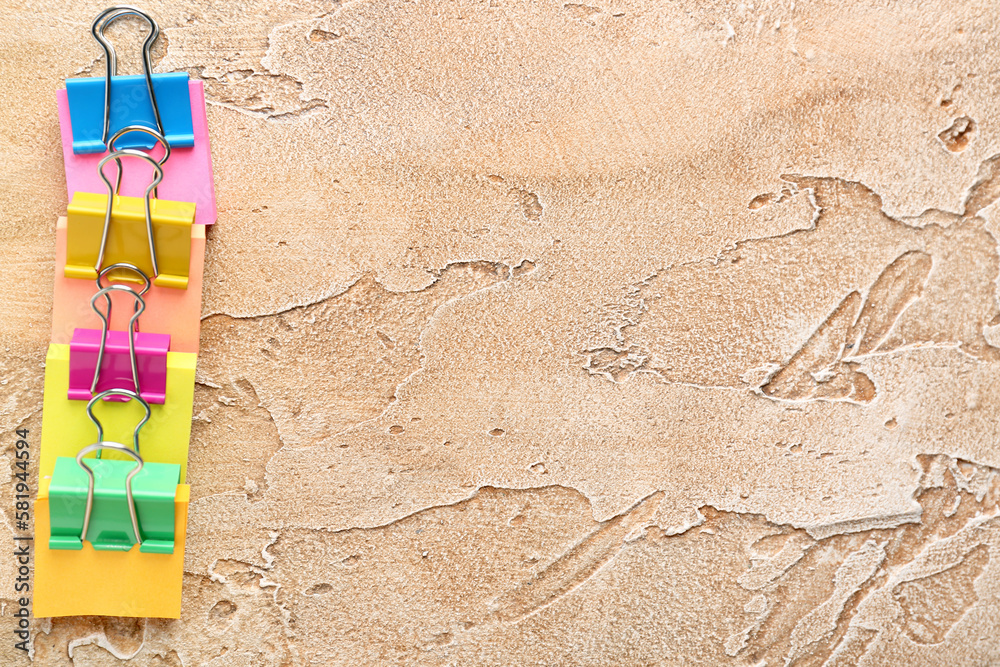 Sticky notes with colorful binder clips on color background