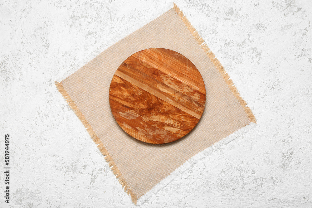 Wooden cutting board and napkin on light background