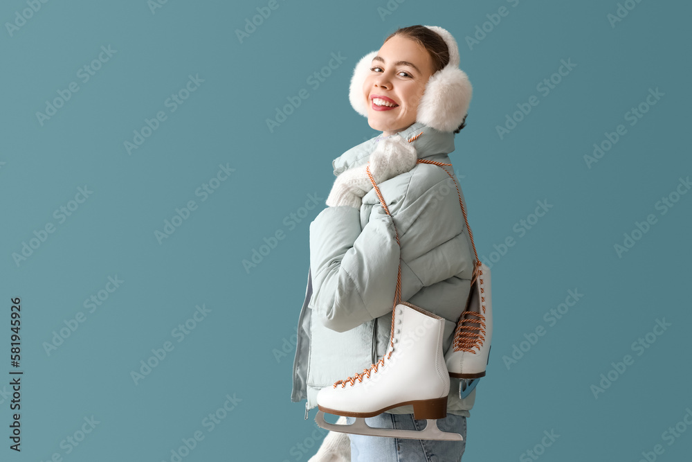 Pretty young woman with ice skates on blue background