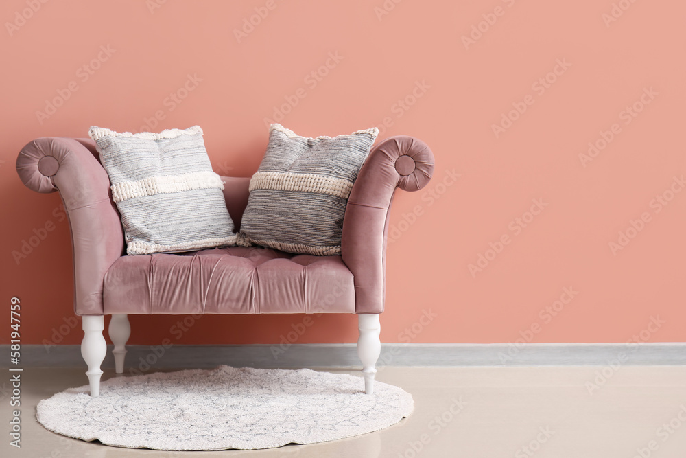 Stylish decorative pillows on cozy armchair near pink wall