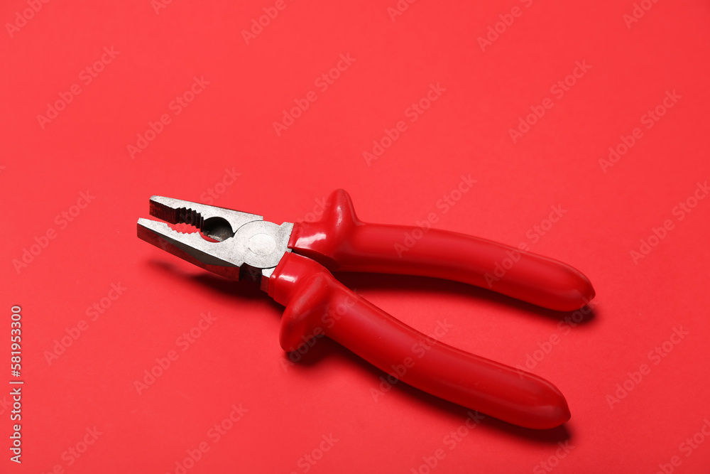 Red pliers on color background