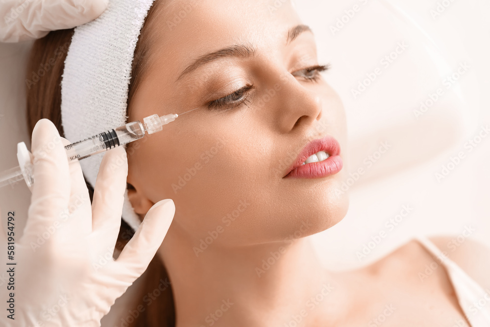 Young woman receiving filler injection  in beauty salon