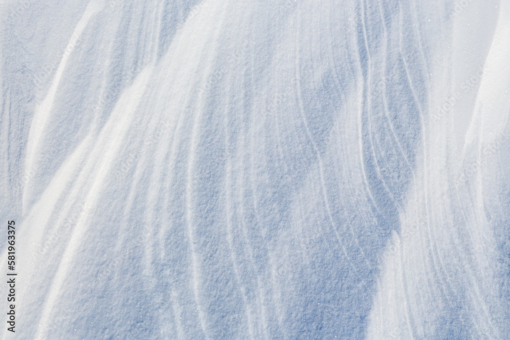 Beautiful winter background with snowy ground. Natural snow texture. Wind sculpted patterns on snow 