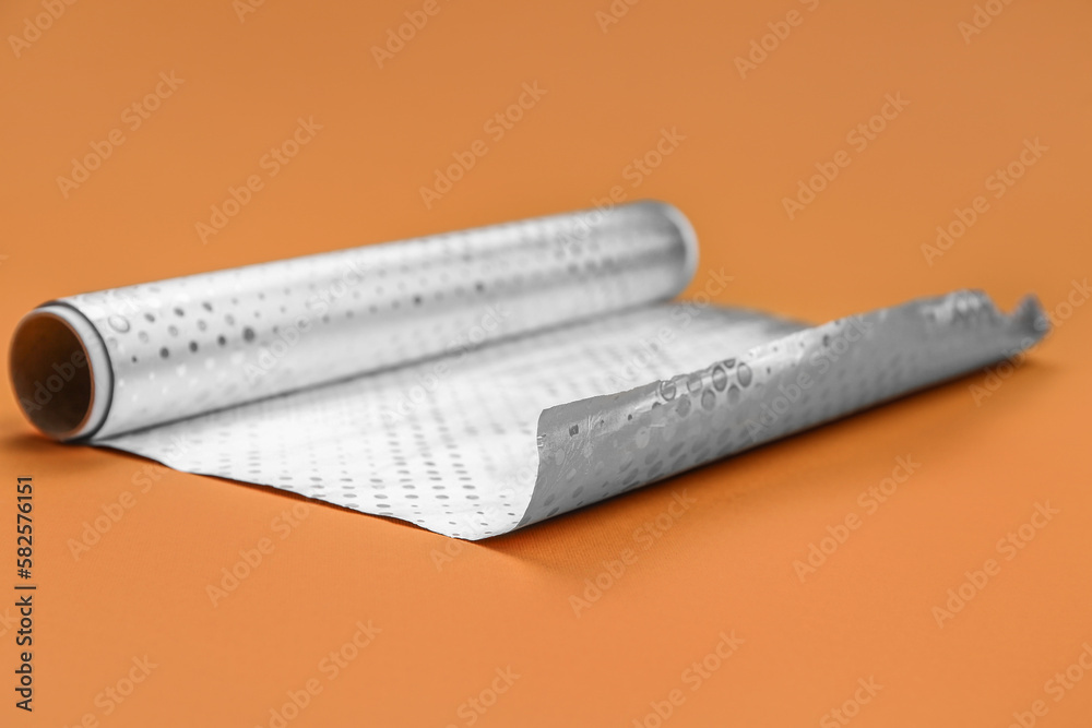 Roll of aluminium foil on orange background