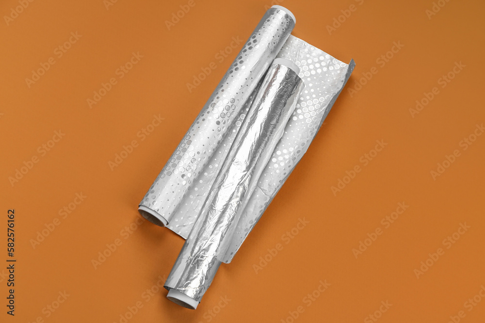 Rolls of aluminium foil on orange background