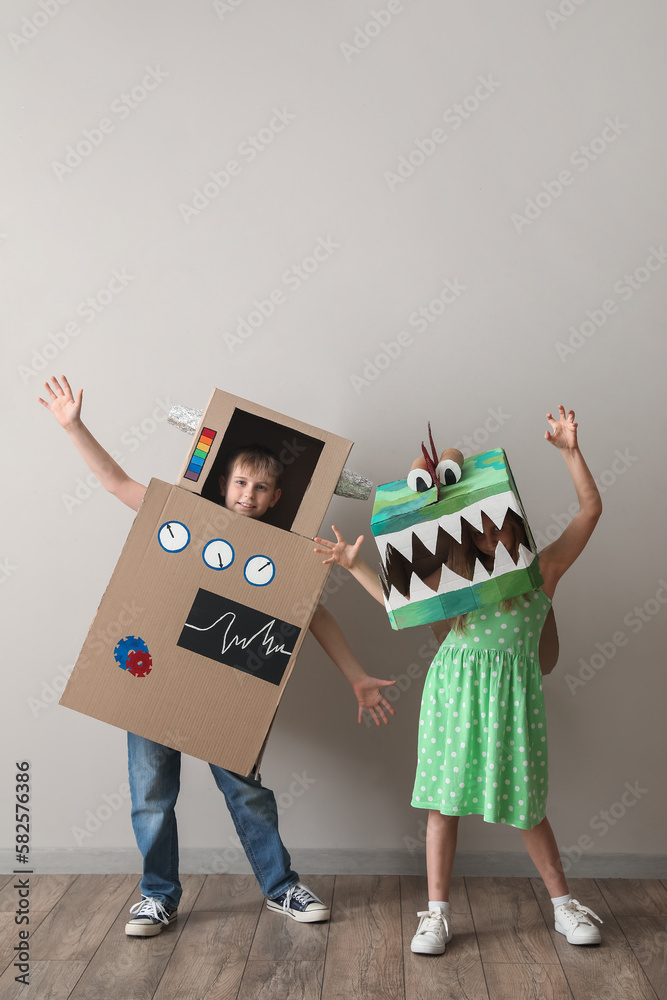 Little children in cardboard costumes playing near light wall