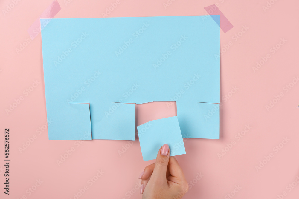 Woman tearing off paper ad on pink background