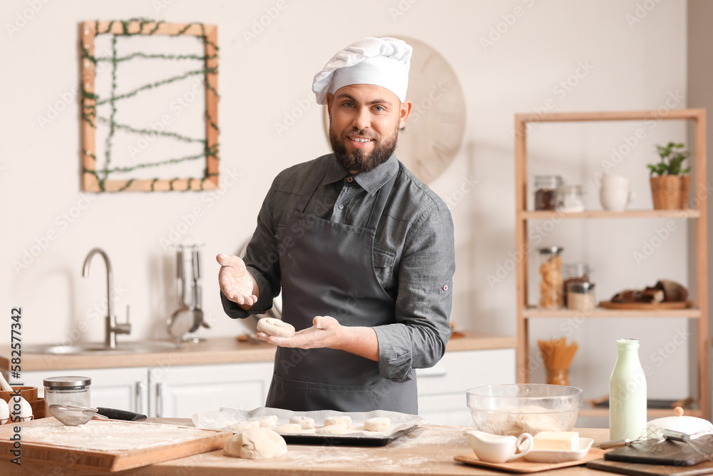 Male baker making buns at table in kitchen