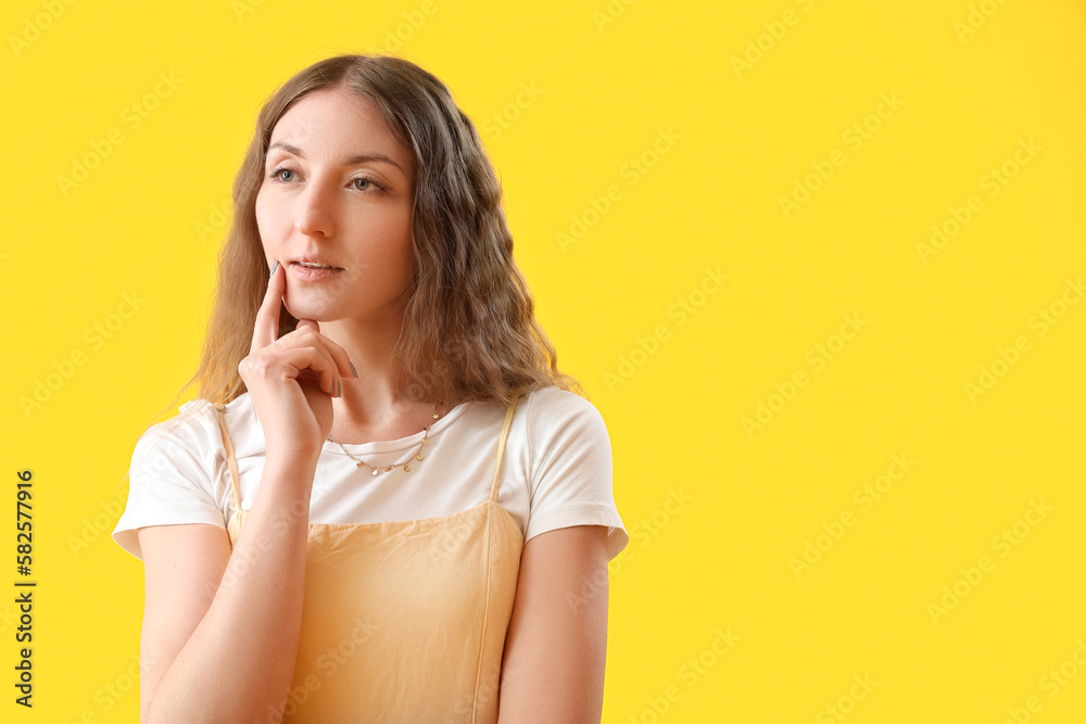 Thoughtful young woman on yellow background