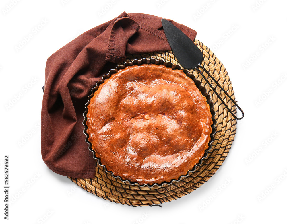 Wicker mat with delicious meat pie in baking form and spatula isolated on white background