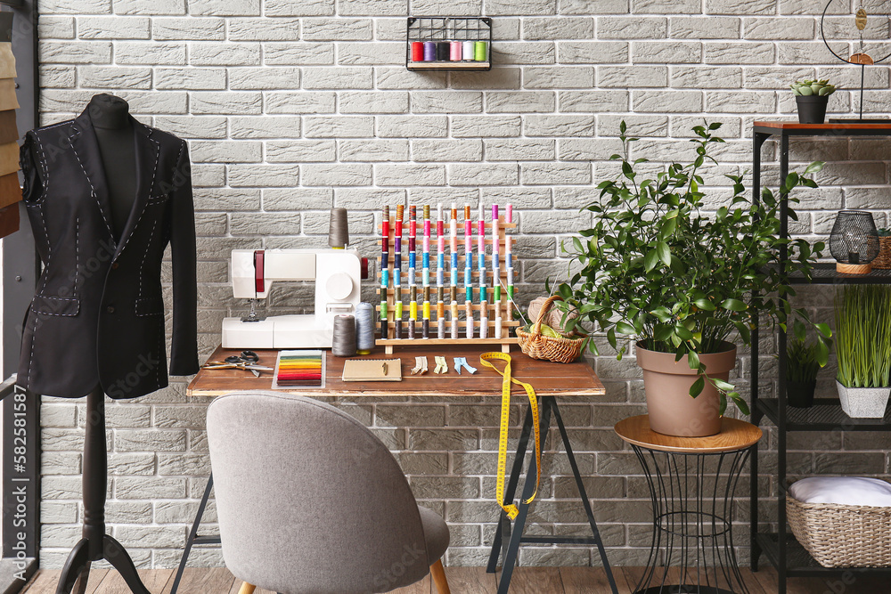 Interior of atelier with tailors workplace, thread spools and mannequin