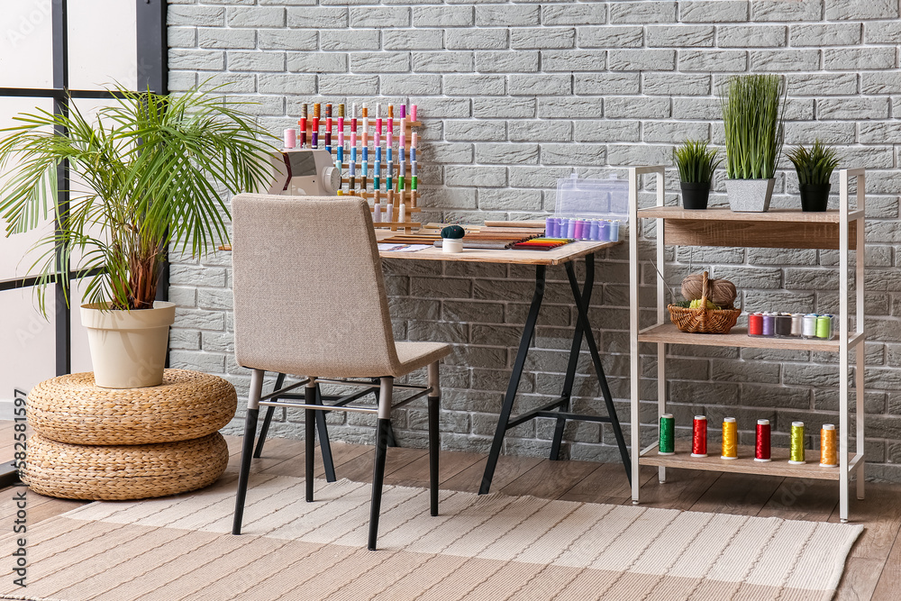 Interior of atelier with tailors workplace, thread spools and shelving unit