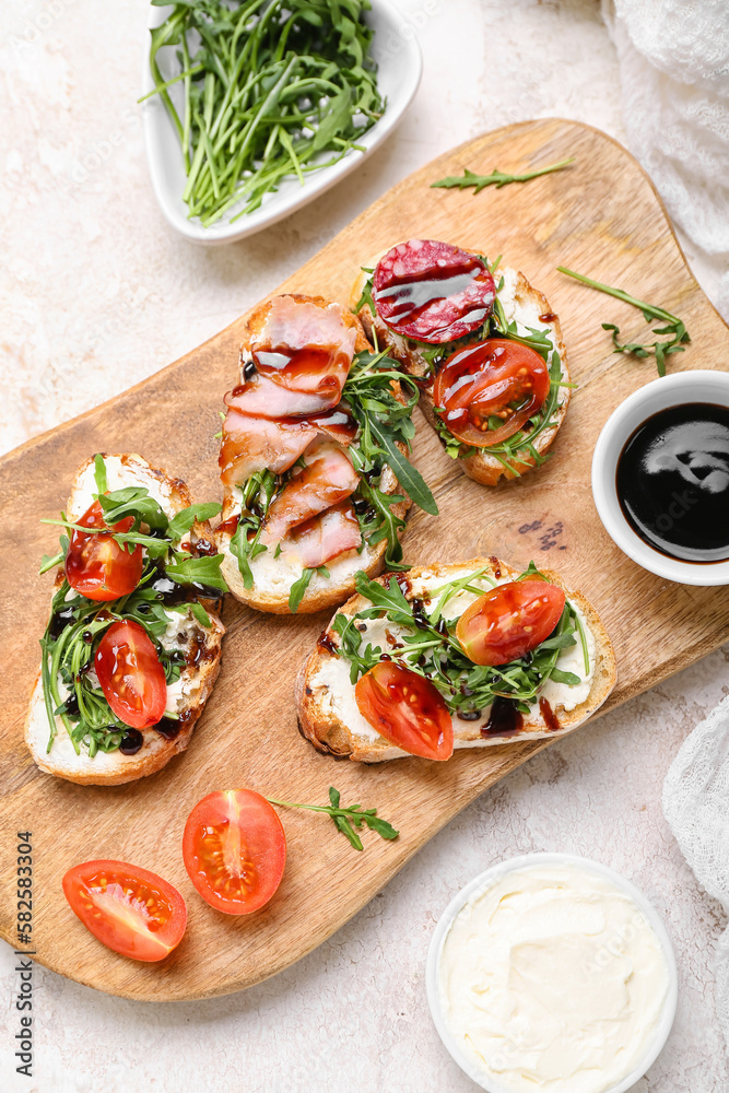 Wooden board with delicious sandwiches and sauce on light background, closeup