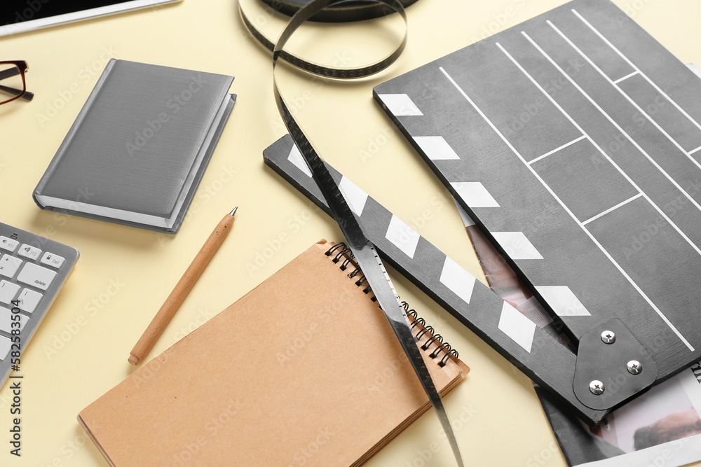 Notebooks with movie clapper and film reel on beige background, closeup