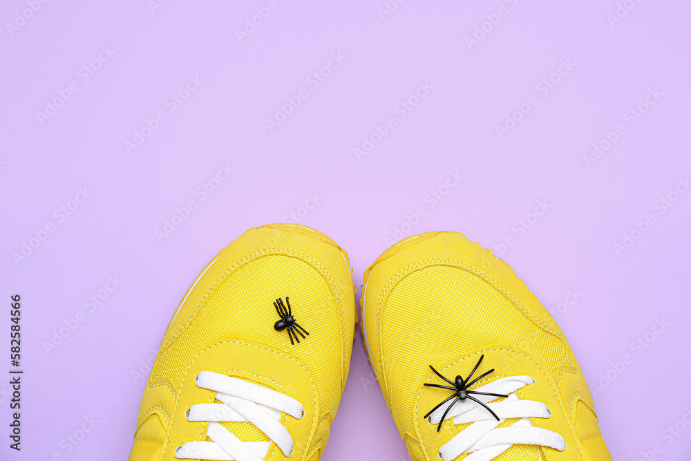 Sneakers with spiders on lilac background, closeup. April Fools Day celebration