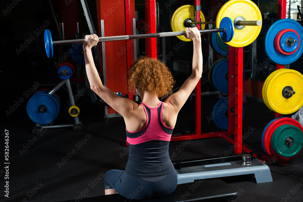 Woman bodybuilder engaged with a barbell in the gym