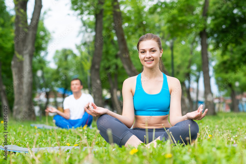 Girl meditates in lotus pose on green grass