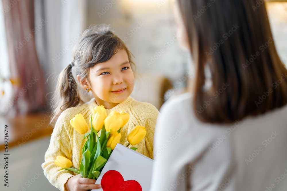 Daughter giving mother bouquet of flowers.