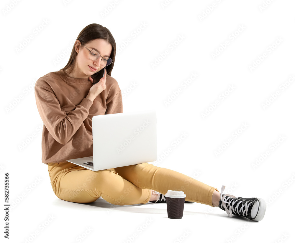 Busy young woman with laptop talking by phone while sitting against white background