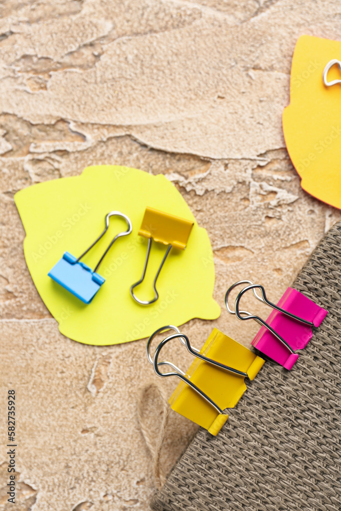 Notebook, binder clips and sticky notes on color background, closeup