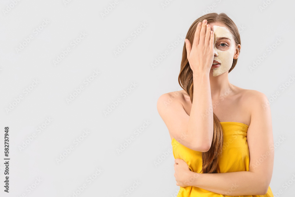 Young woman with applied turmeric mask on grey background