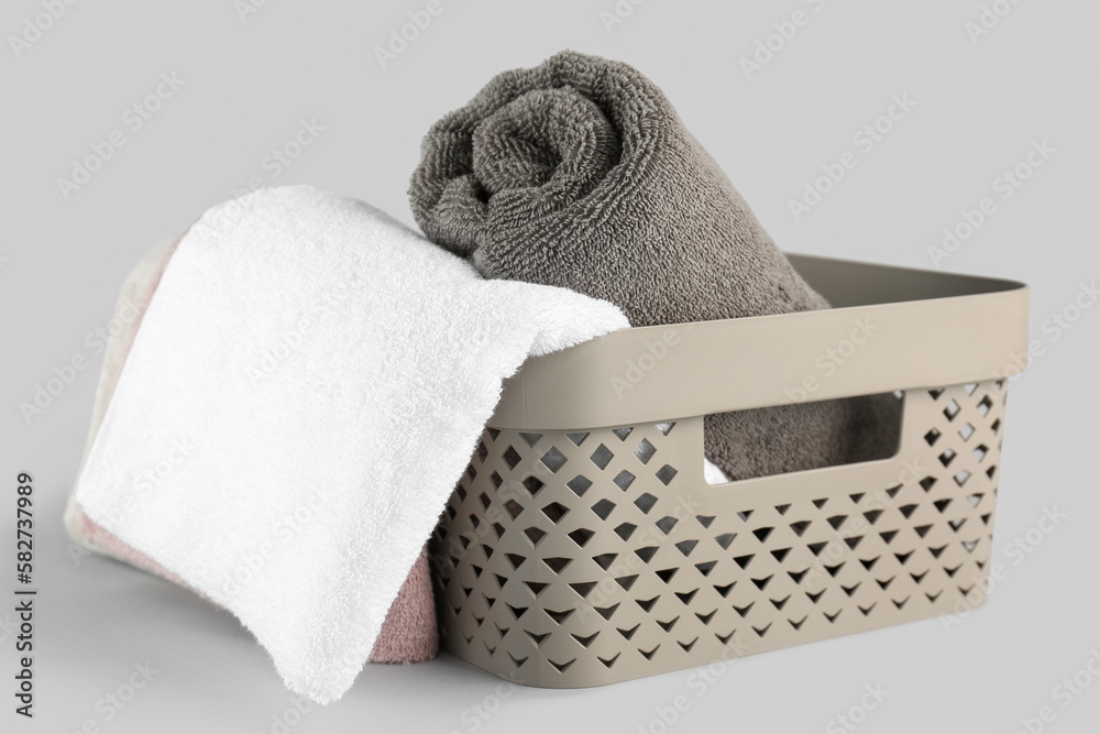 Basket with cotton soft towels on grey background