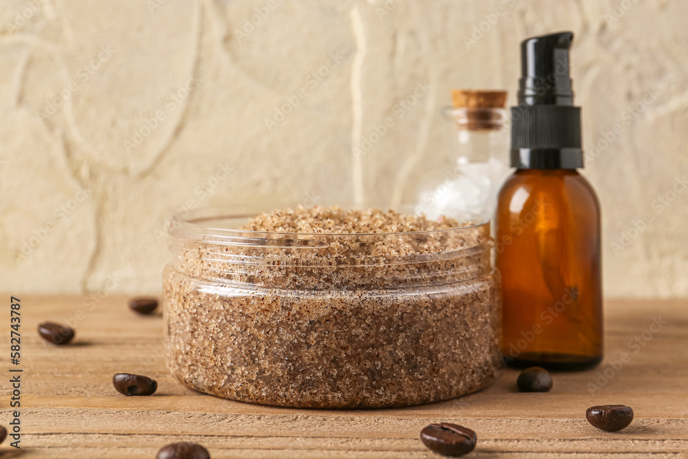 Jar of body scrub, sea salt, essential oil and coffee beans on wooden table