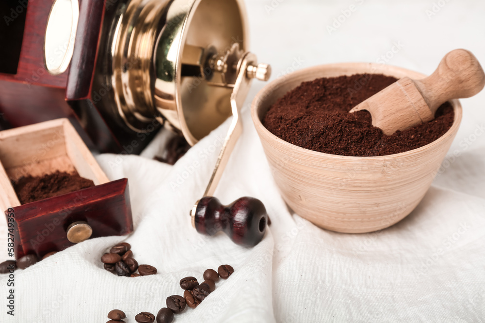 Bowl of coffee powder with scoop and grinder on white napkin, closeup